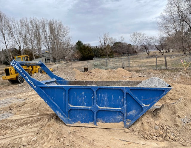 A blue bedding box on a construction site filled with gravel.