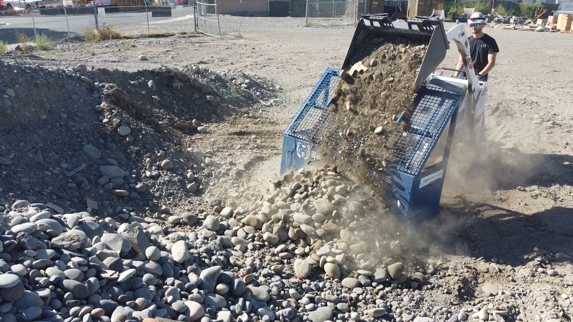 a walk behind skid steer screening soil with a grizzly rock screen